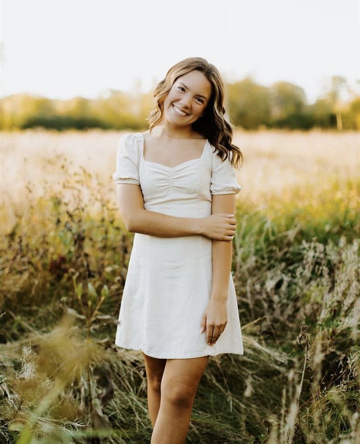 a woman in a white dress standing in tall grass