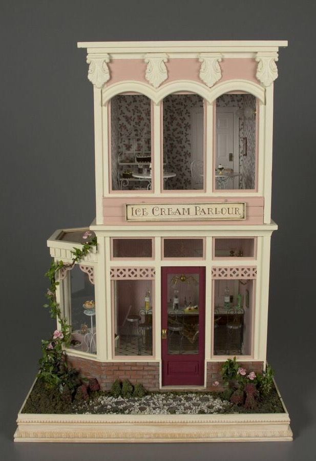 a doll house with pink and white trimmings on the front door, windows and doors