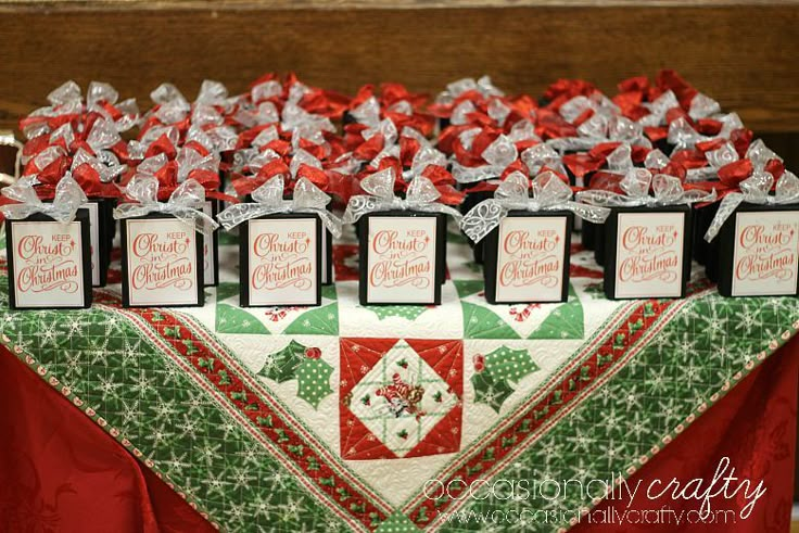 a table topped with lots of small boxes filled with christmas gifts on top of a red and green table cloth