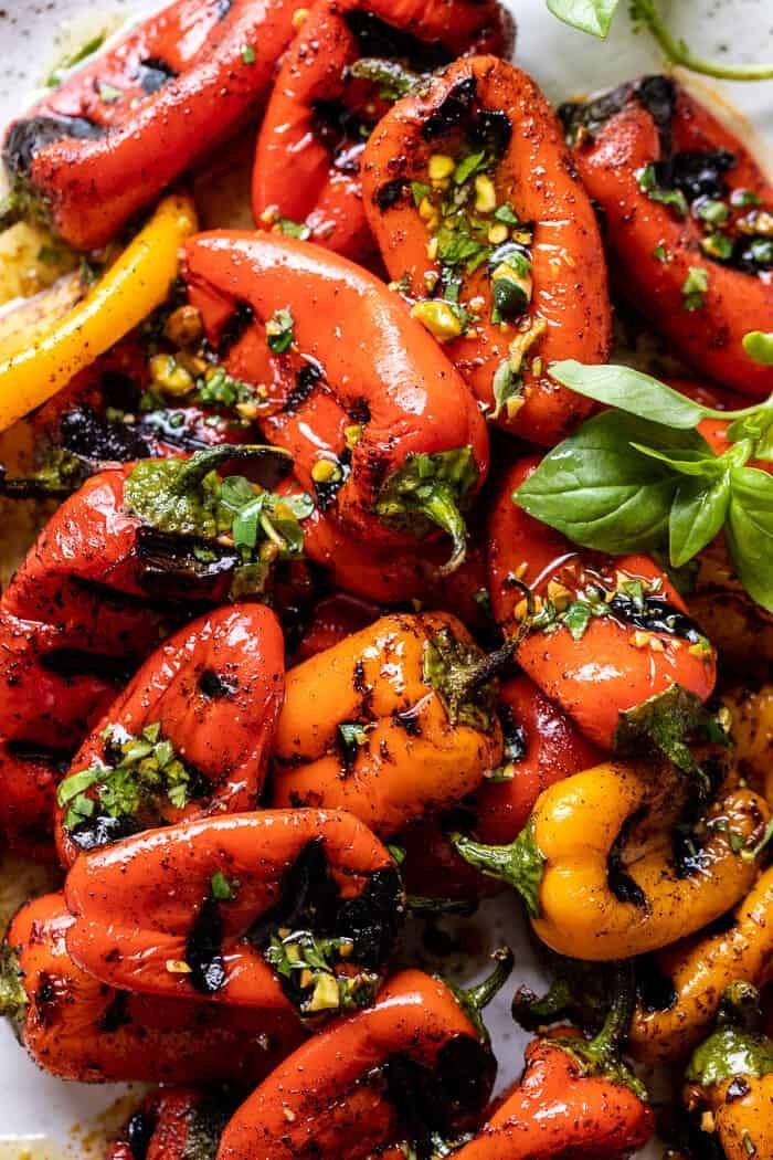 grilled red peppers with herbs and lemon on a white platter, ready to be eaten