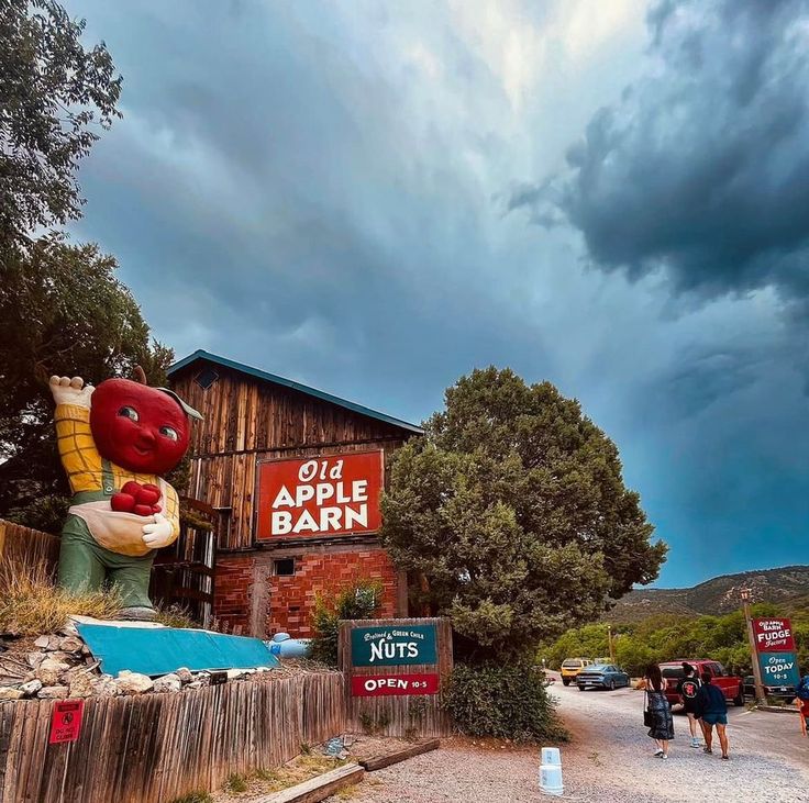 an old apple barn with people walking past it on a cloudy day in the mountains