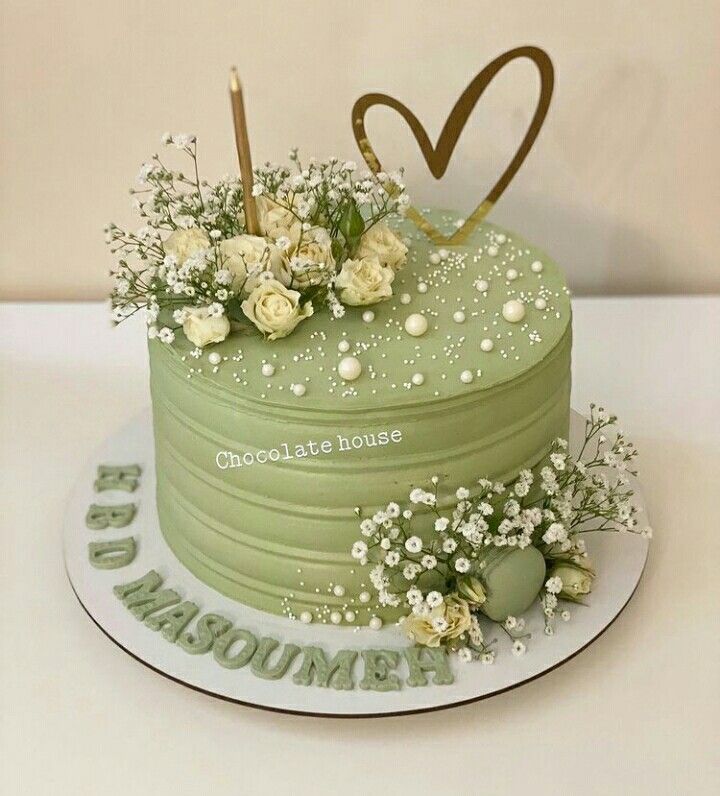 a green cake with white flowers on top and the words chocolate house written in gold