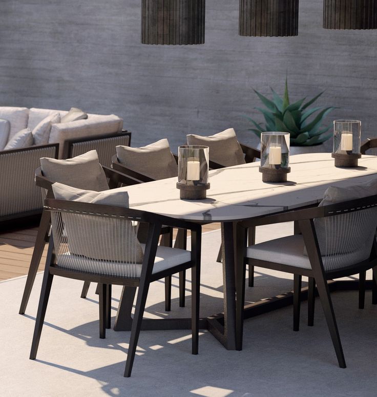 an outdoor dining table with chairs and candles on the top, in front of a concrete wall