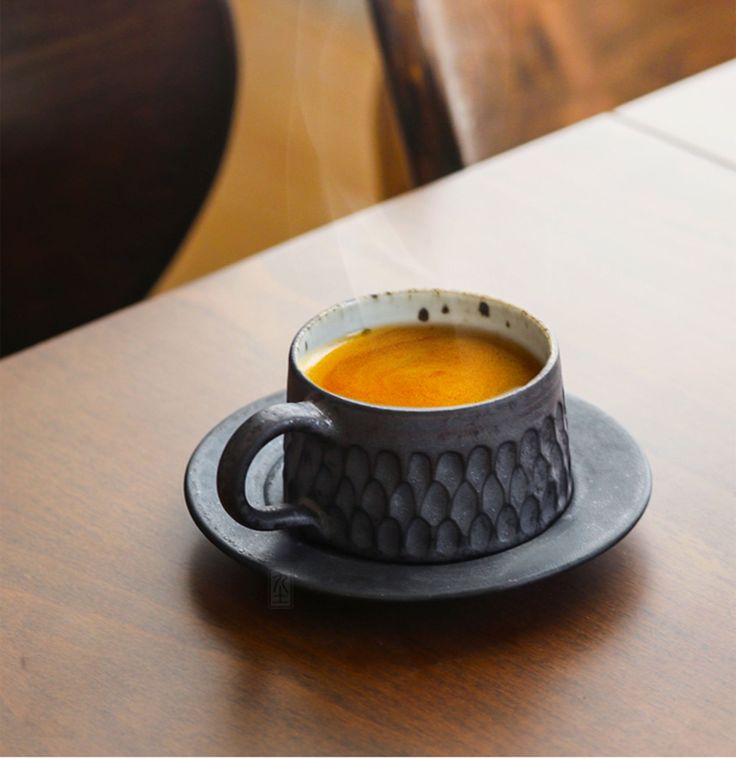 a cup of soup sitting on top of a wooden table