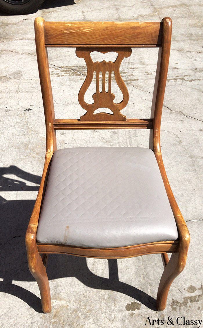 a wooden chair sitting on top of a parking lot next to a white seat cushion