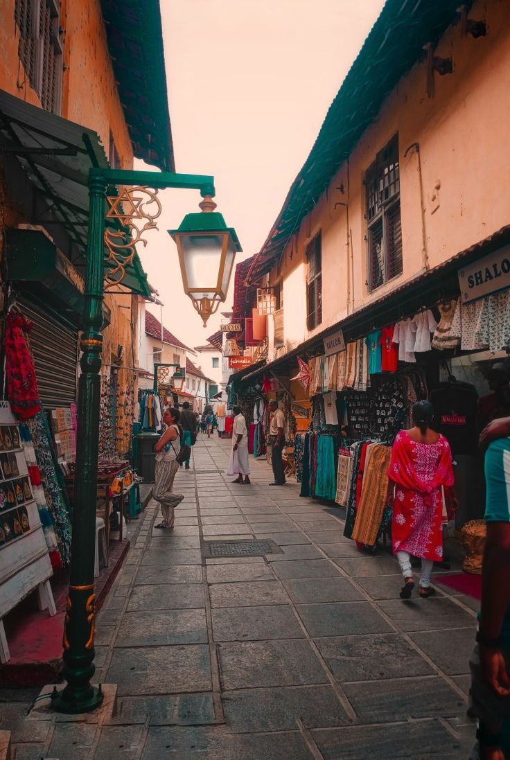 people are walking down the street in front of shops