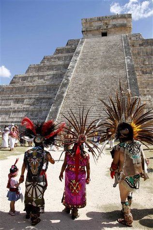 three people in native garb standing next to an ancient pyramid