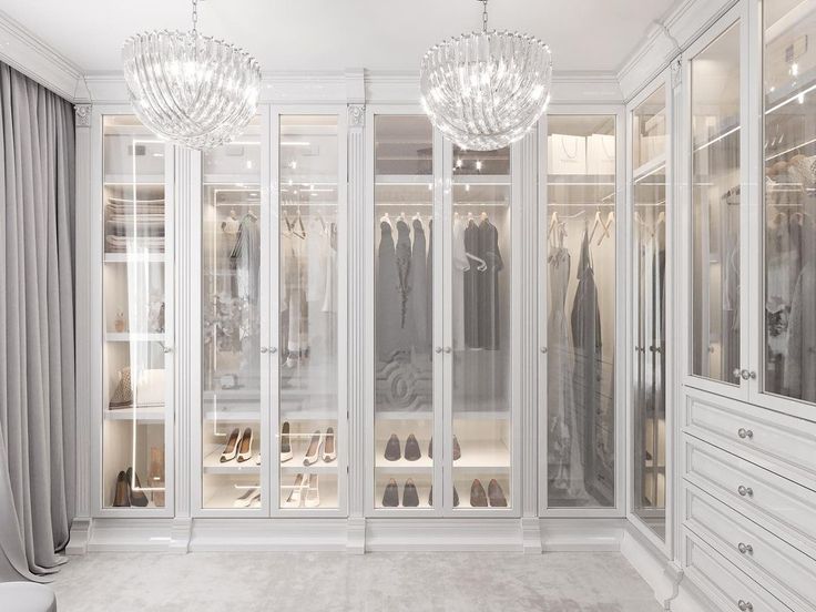 a walk in closet with chandelier and shoes on the shelves next to it