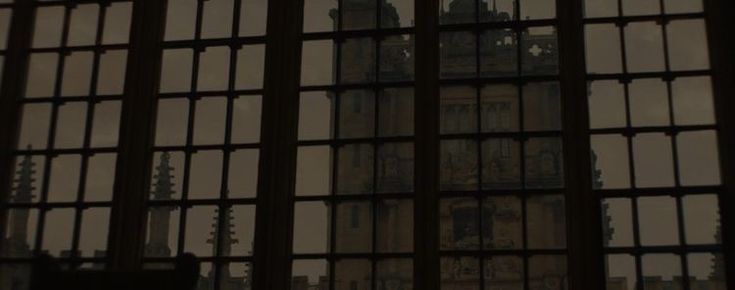 the clock tower is seen through many windows in an old building with iron bars on it's sides