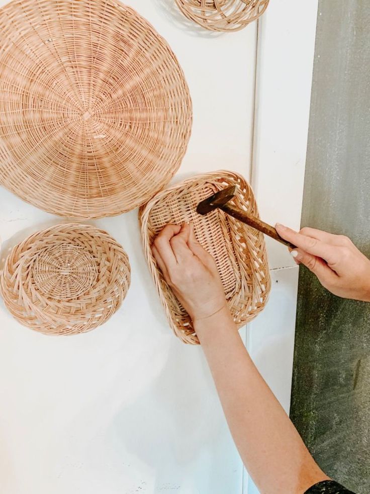 a woman is painting wicker baskets on the wall