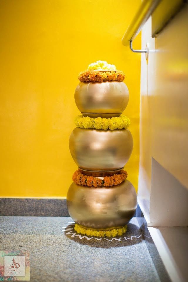 a stack of three metal vases sitting on top of a floor next to a yellow wall