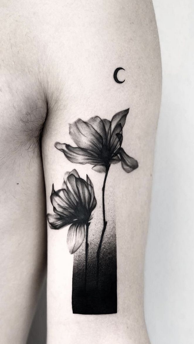 a black and white photo of flowers on the back of a man's arm