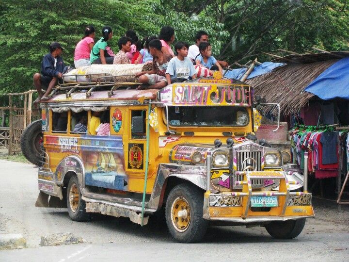 people are sitting on the roof of an old bus that is painted yellow and decorated with colorful designs