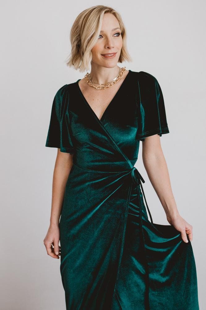 a woman wearing a green velvet wrap dress