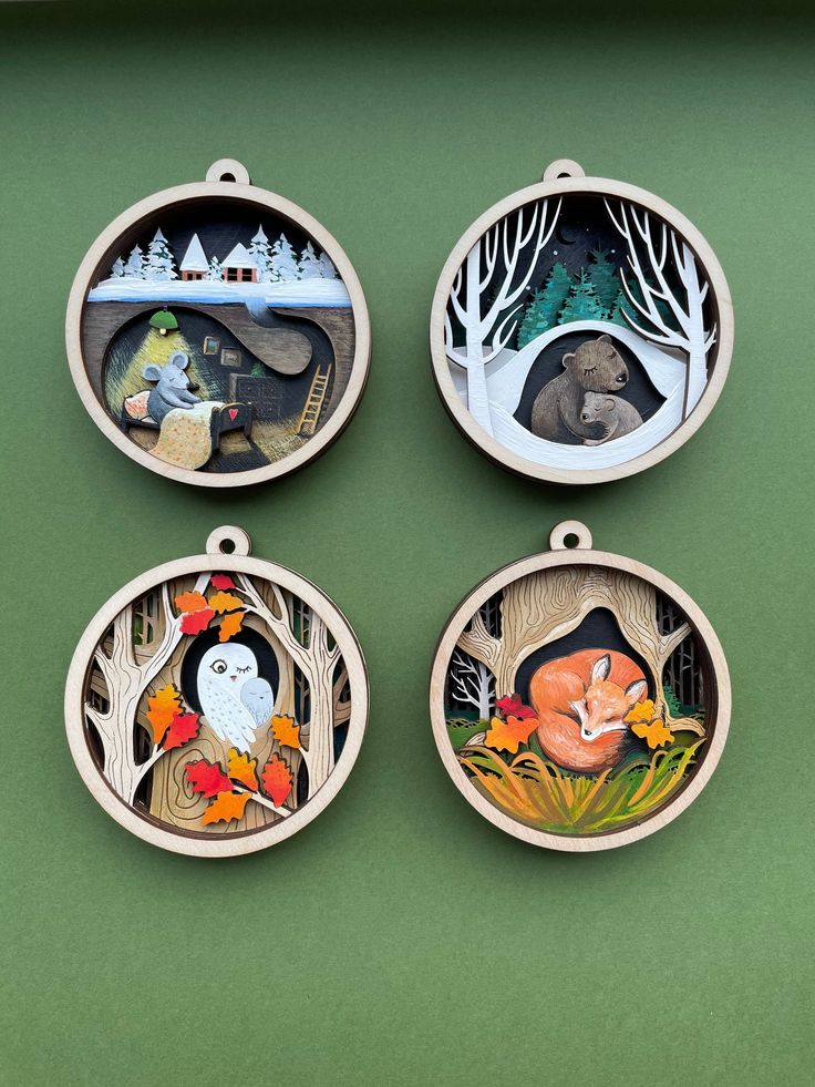 four wooden ornaments with animals and trees on them are hanging from a green wall in the shape of circles