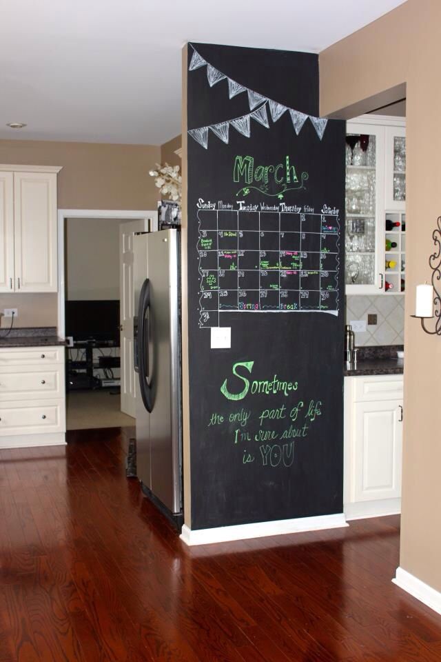 a kitchen with a refrigerator and chalkboard on the wall