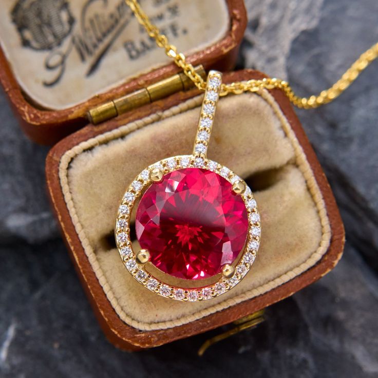 This sparkling pendant necklace is centered with a large round lab created ruby cut to brilliant perfection. Surrounding the ruby and climbing up the bale are thirty-six round brilliant cut diamonds, all set in 14k yellow gold. The pendant hangs from 14k yellow gold, 18 inch long cable chain with jump rings so it can also be worn at 16 and 17 inches as well. Luxury Lab-created Ruby Necklace Gift, Fine Jewelry Ruby Diamond Necklace Brilliant Cut, Luxury Red Diamond Round Necklace, Luxury Red Diamond Necklace, Luxury Red Round Diamond Necklace, Fine Jewelry With Lab-created Ruby In Yellow Gold, Yellow Gold Jewelry With Lab-created Ruby, Fine Jewelry Yellow Gold Lab-created Ruby, Yellow Gold Jewelry With Lab-created Ruby In Prong Setting