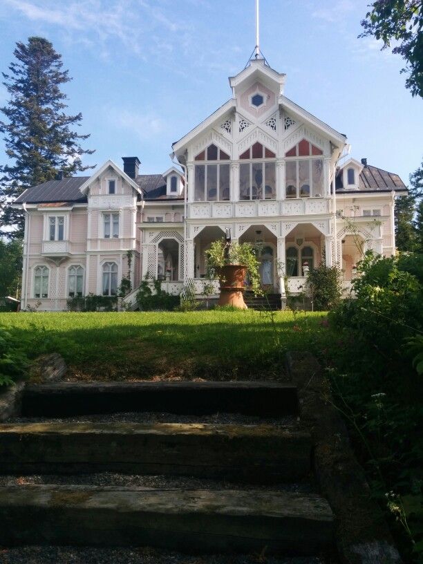 a large white house sitting in the middle of a lush green field with stairs leading up to it