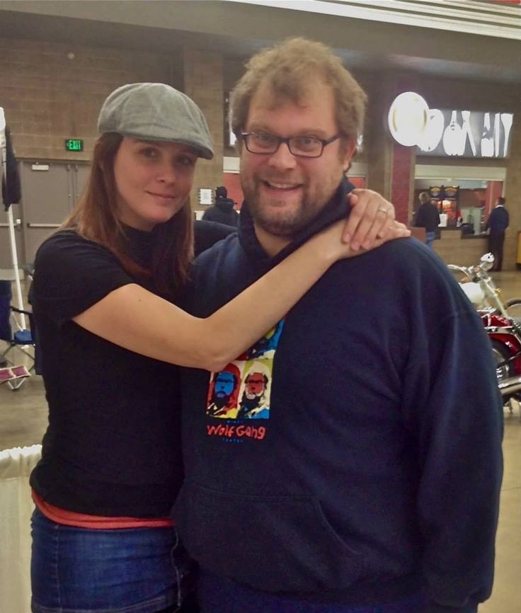 a man and woman standing next to each other in front of a motorcycle show room