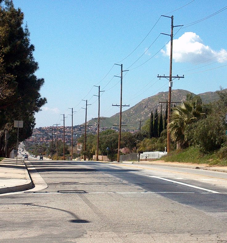 an empty street with no cars on it and telephone poles in the foreground as well