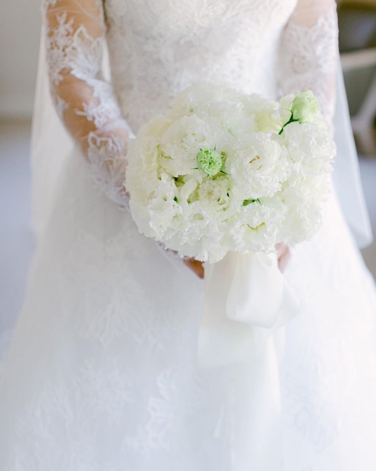 a bride holding a bouquet of white flowers