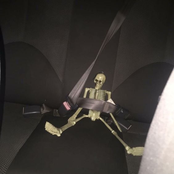 a skeleton sitting in the back seat of a car