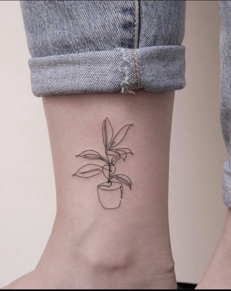 a woman's ankle with a small plant tattoo on her left side ribcage