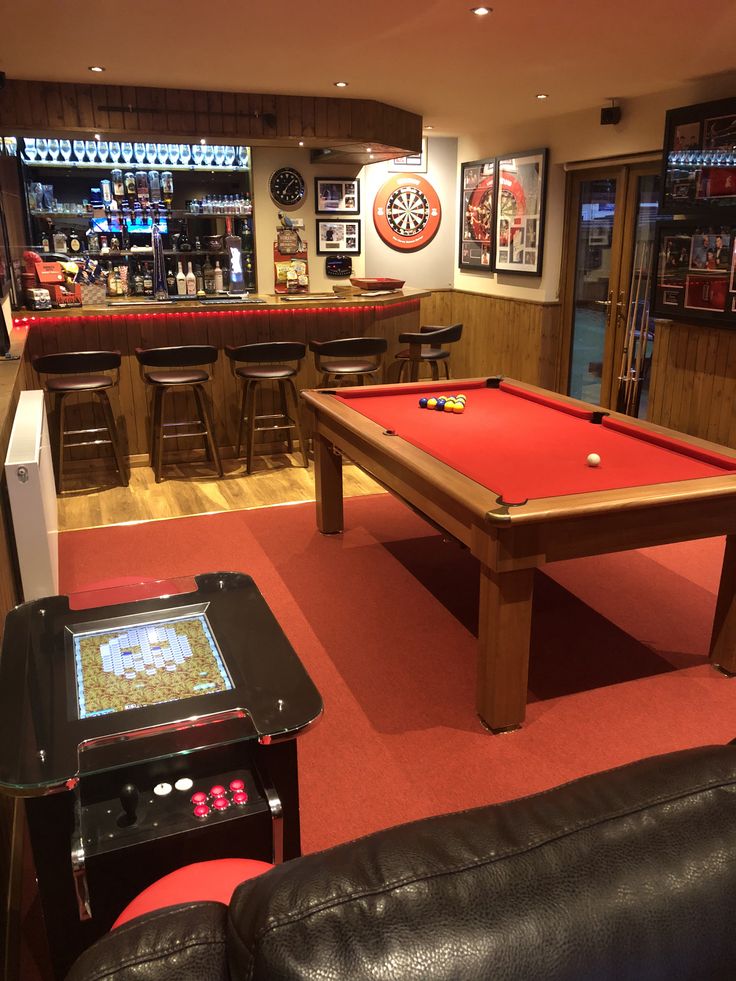 a pool table in the middle of a living room with bar stools around it