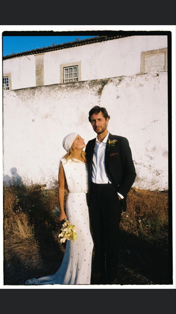 a man and woman standing next to each other in front of a white building with windows