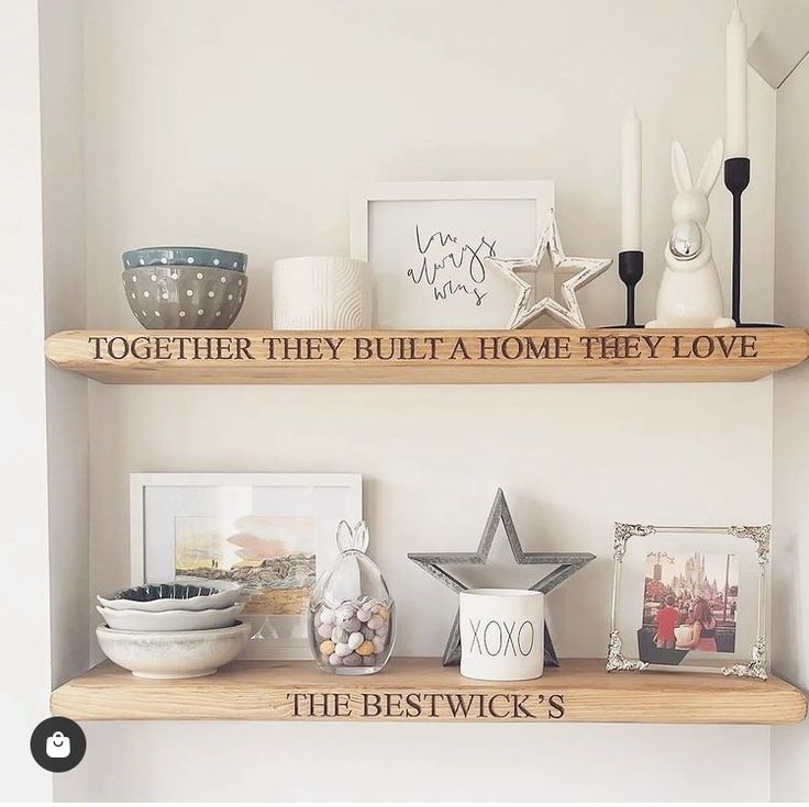 two wooden shelves with pictures, candles and other items on top of them in a white room