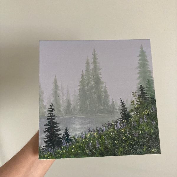 a person holding up a card with trees and water in the background on a white surface