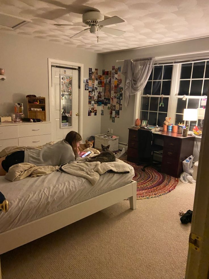 a person laying on a bed in a room with a ceiling fan and a window