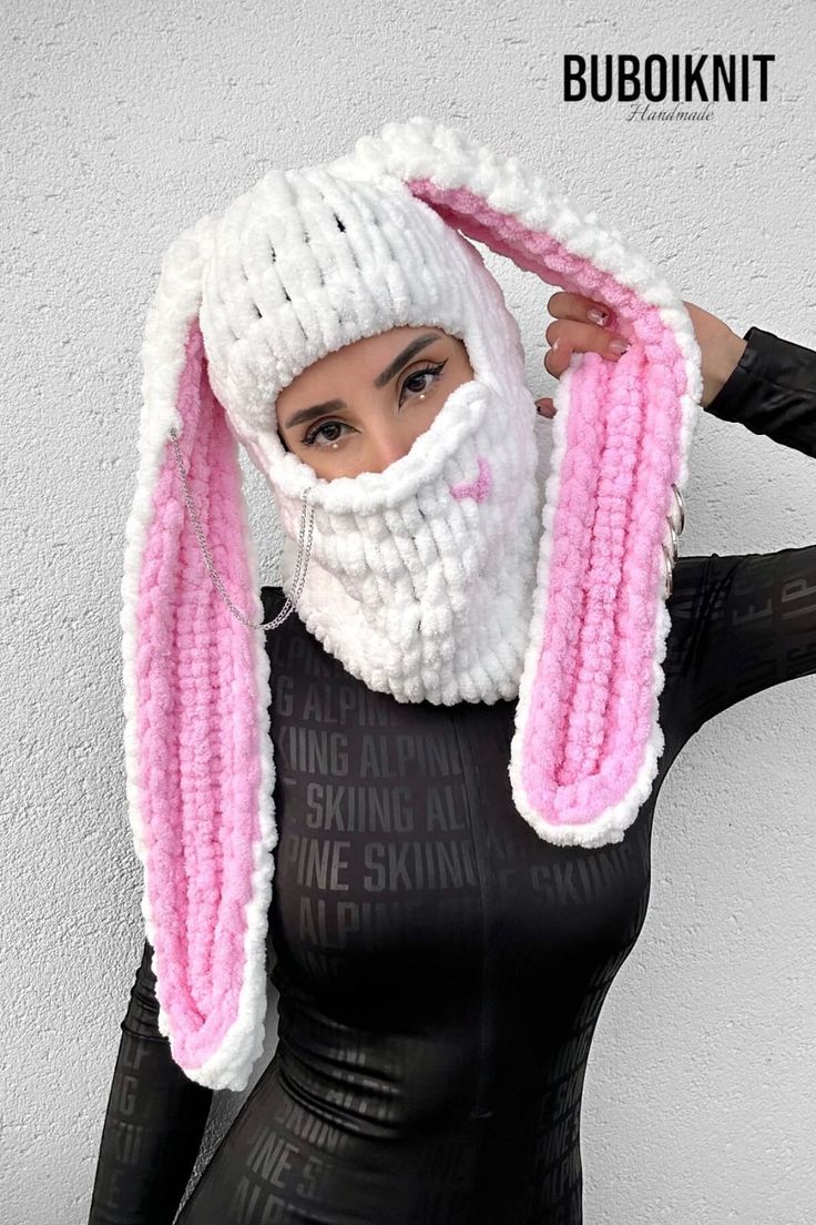 a woman in black latex with pink and white bunny ears on her head wearing a knitted scarf