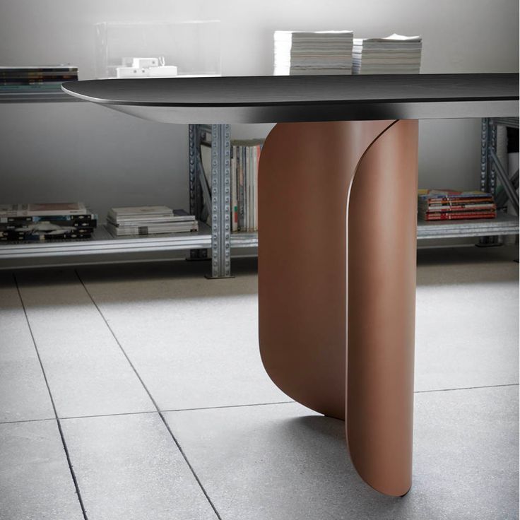 a table that has some kind of curved object on it's base in the middle of a room