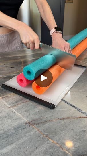 a woman is cutting up some colorful items on the floor with a large pair of scissors