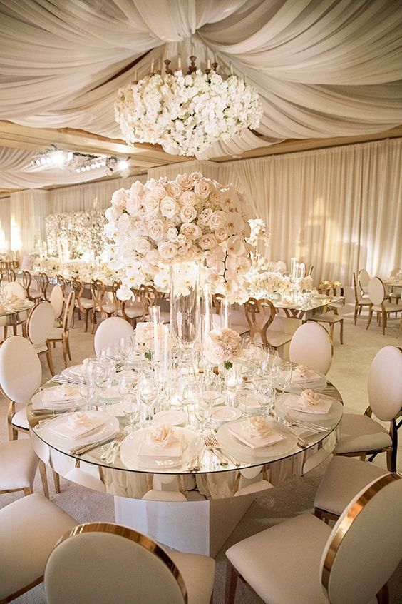 an elegant wedding reception with white flowers and chandeliers on the ceiling, all set up for a formal function