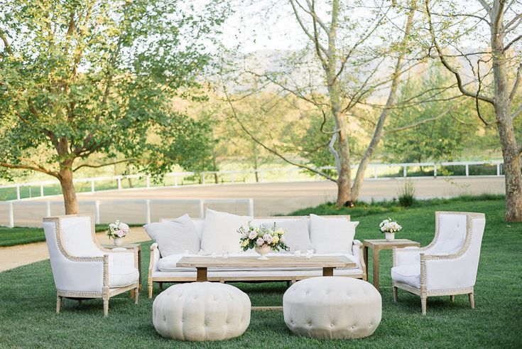 a white couch and chairs sitting on top of a lush green field