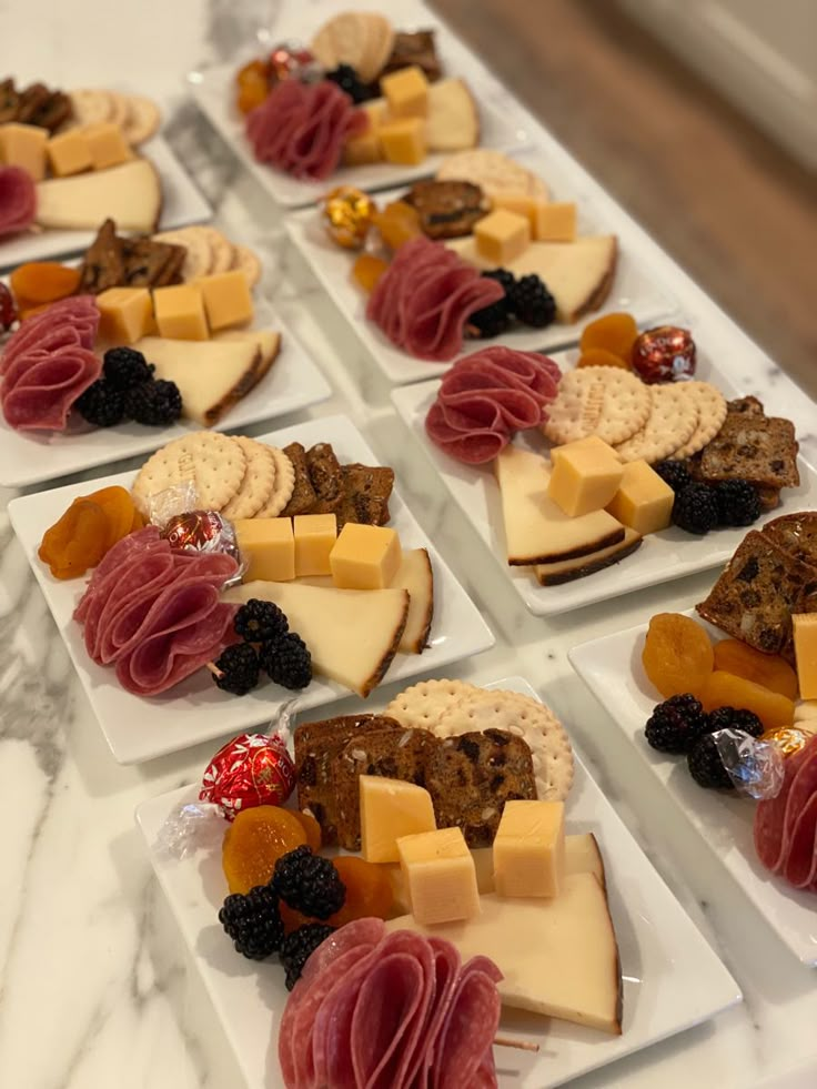 many different types of cheeses and crackers on small white plates sitting on a marble table