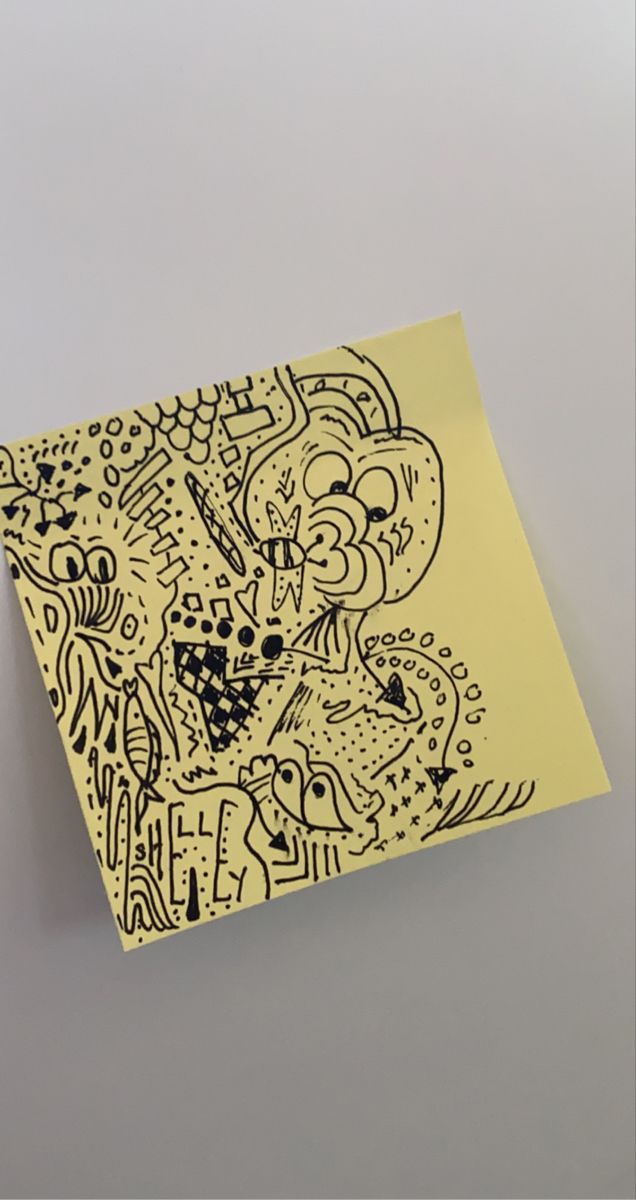 a piece of yellow paper with black and white drawings on it, against a gray background