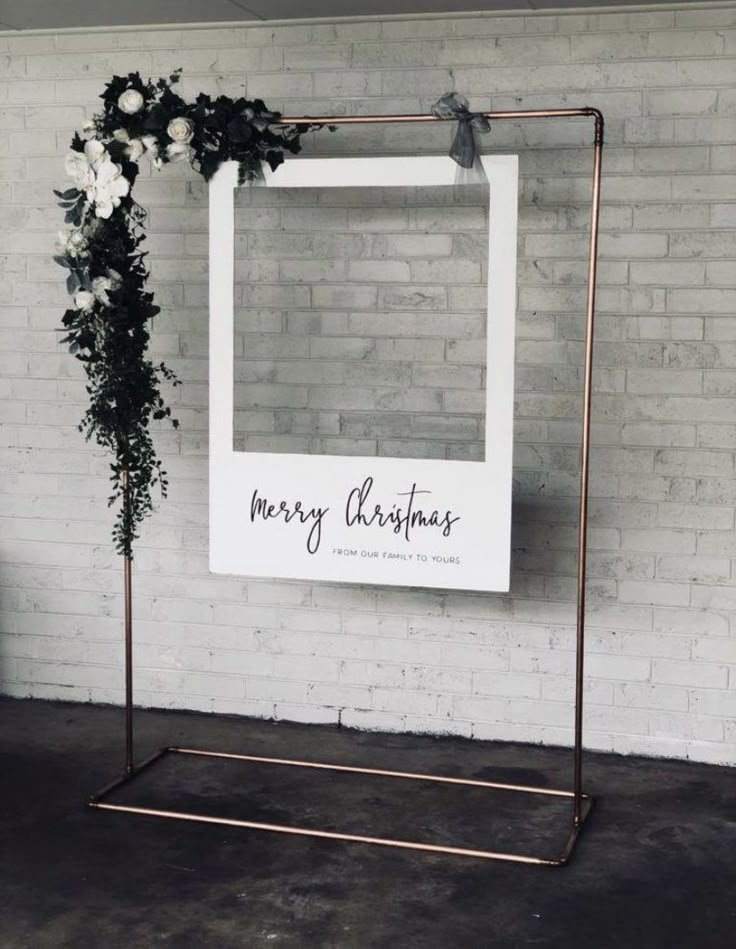 a sign that says merry christmas on it next to a chair and potted plant