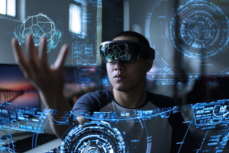 a man wearing virtual reality glasses in front of computer screens