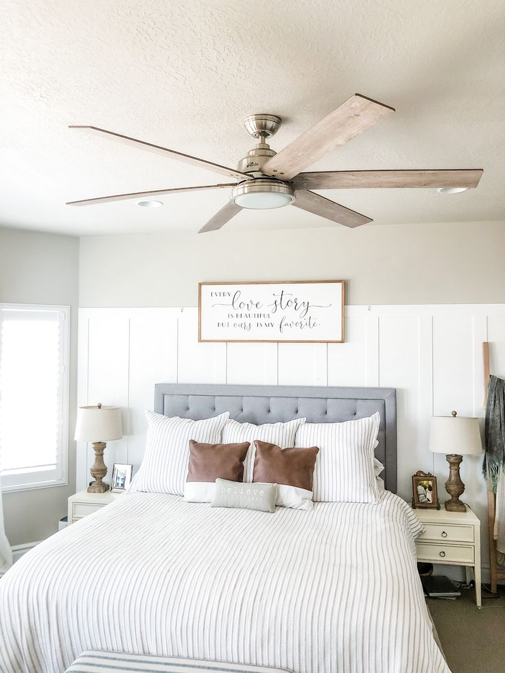 a bedroom with a bed, ceiling fan and two lamps on either side of the bed