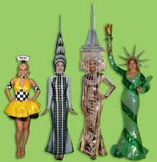 three women dressed in costumes standing next to each other on a green background with the statue of liberty behind them