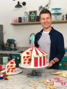 a man standing in front of a cake with a circus tent on top of it