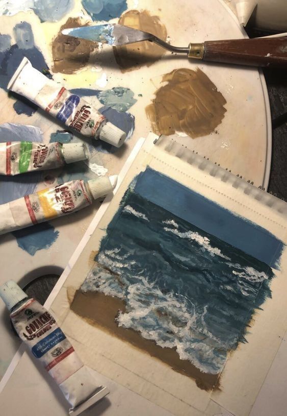 an artist's palette with paint and watercolors on it