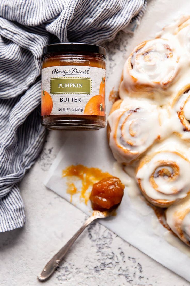 cinnamon buns with icing next to a jar of butter