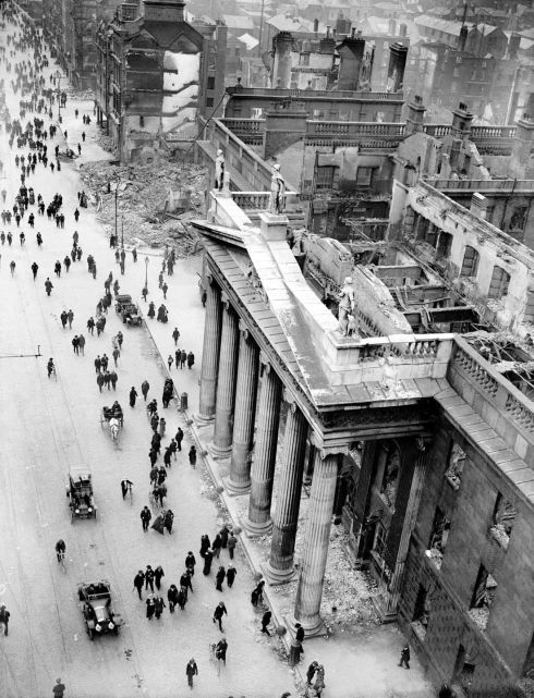 black and white photograph of people walking down the street in an old time cityscape