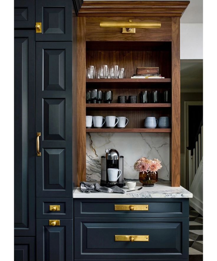 a kitchen with black cabinets and marble counter tops, gold pulls on the door knobs