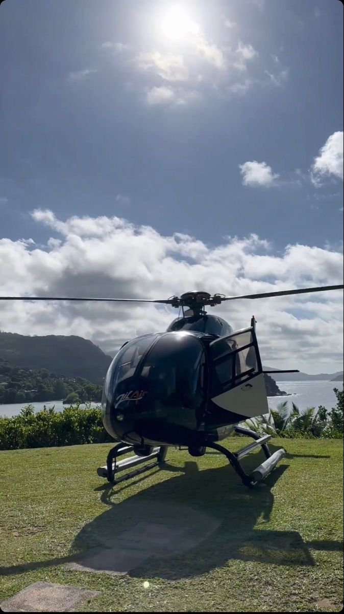 the helicopter is parked on the grass by the water