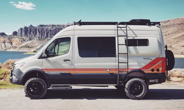 an off road camper van parked in front of a lake